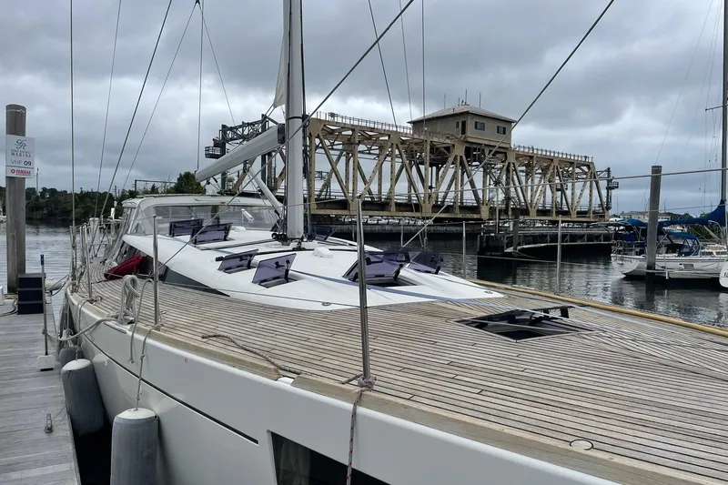 Slide: The Image of 2017 Beneteau Sense 50 yacht docked near a bridge on a cloudy day. - 11