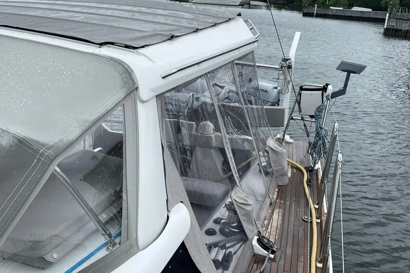 Slide: The Image of 2017 Beneteau Sense 57 yacht with covered cockpit, docked on a calm waterway. - 124