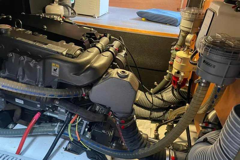 Slide: The Image of Engine room of a 2017 Beneteau Sense 50 yacht, showcasing complex machinery and hoses. - 46