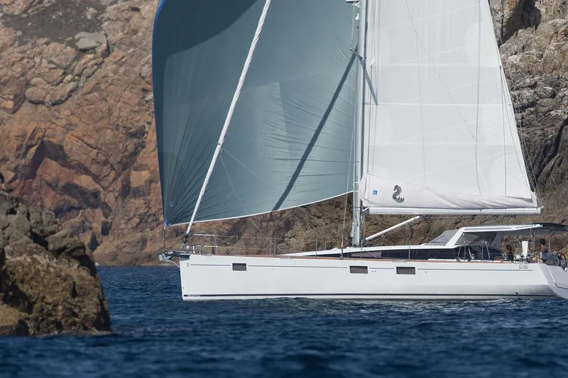 Slide: The Image of 2017 Beneteau Sense 50 sailing near rocky coastline, showcasing elegant design and performance. - 82