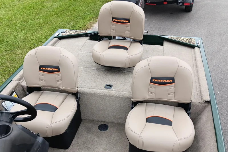 Slide: The Image of 2026 Tracker Bass Tracker Classic Limited boat seats, beige with orange accents, on a carpeted deck. - 12