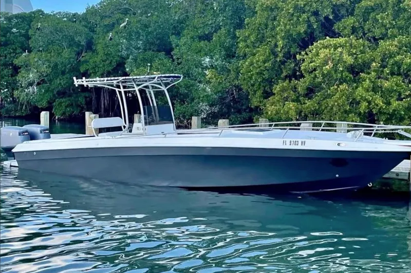 The Image of 1980 Wellcraft Scarab 302 boat docked by lush green trees. - 0