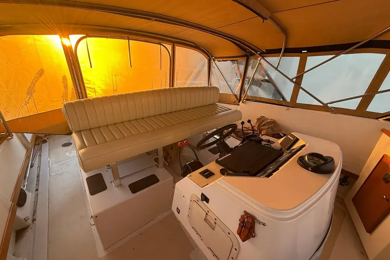 Slide: The Image of 1979 Magnum 38 Sport boat interior with helm, beige seating, and sunset glow. - 23
