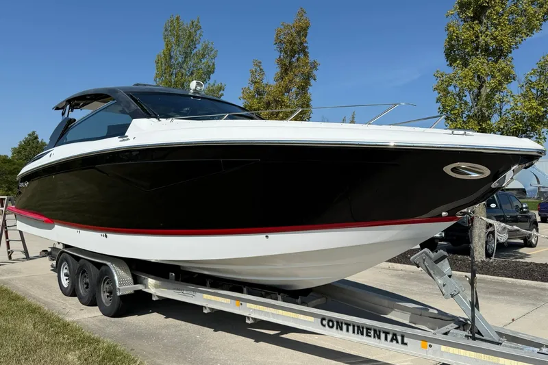 The Image of 2019 Cobalt A36 boat on trailer, sleek black and white design, parked outdoors. - 1