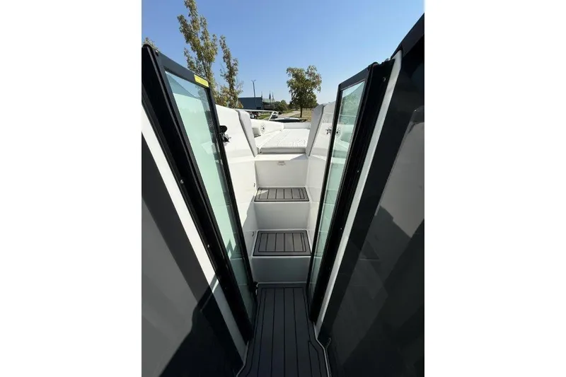 Slide: The Image of 2019 Cobalt A36 boat interior with open glass doors and steps, under clear blue sky. - 23