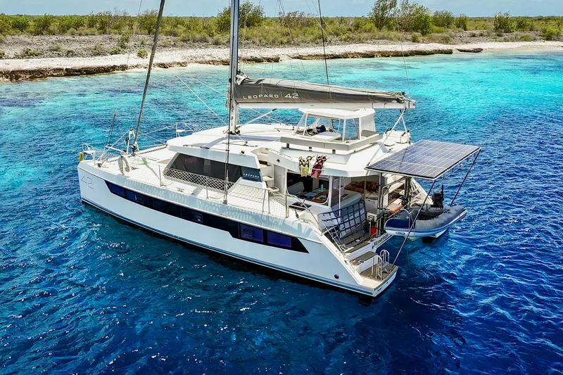 Slide: The Image of 2023 Leopard 42 catamaran sailing in clear blue waters near a tropical shoreline. - 12