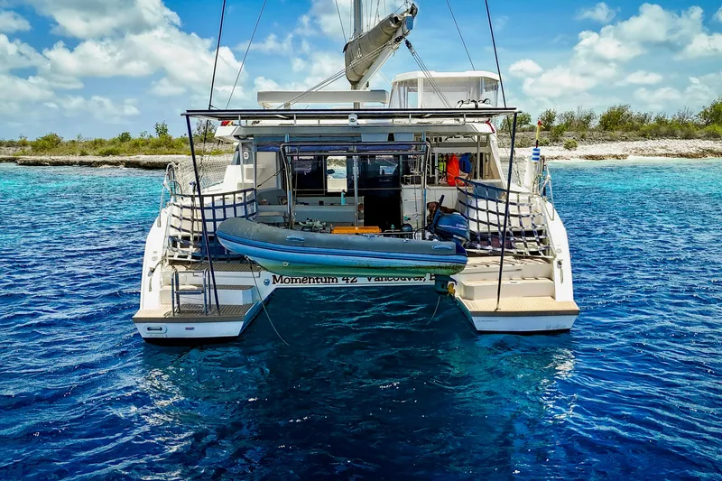 Slide: The Image of 2023 Leopard 42 catamaran anchored in clear blue water, with dinghy attached. - 13