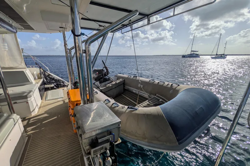 Slide: The Image of Leopard 42 catamaran deck with dinghy, ocean view, and distant sailboats, 2023 model. - 34