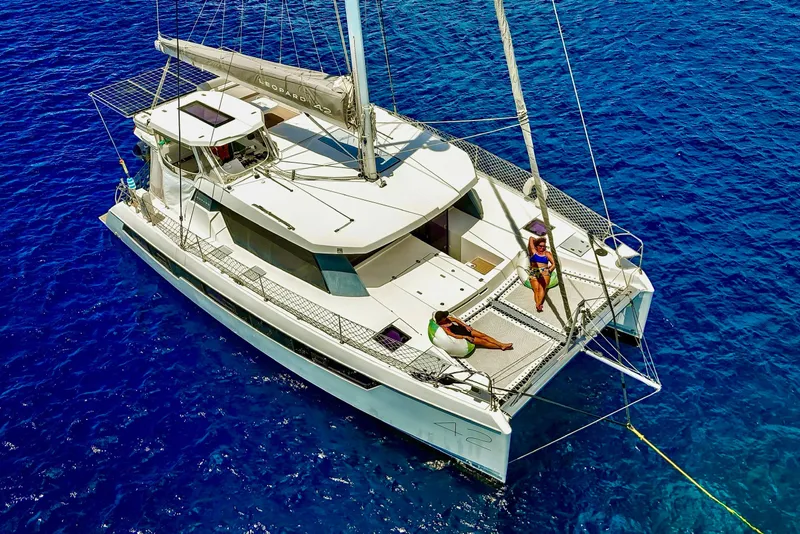 Slide: The Image of 2023 Leopard 42 catamaran sailing on clear blue ocean with two people relaxing on deck. - 4