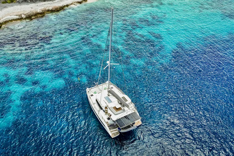 Slide: The Image of Aerial view of 2023 Leopard 42 catamaran on vibrant blue ocean near rocky shoreline. - 99