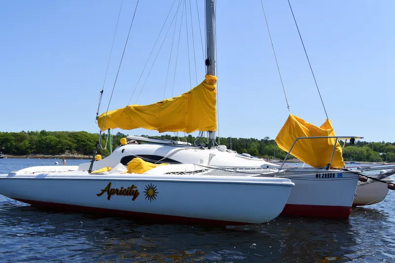 The Image of Sailboat Corsair F-24 MKII #299, 1999, with yellow sails, named "Apricity" on calm water. - 0