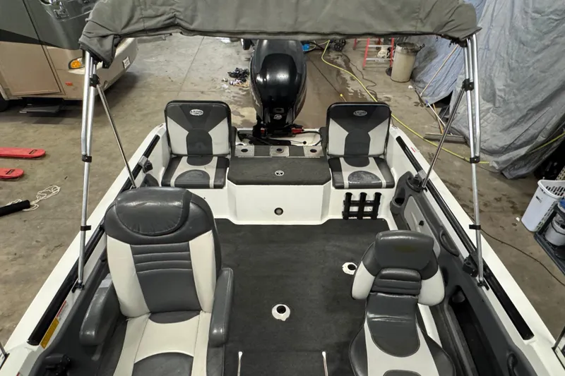 Slide: The Image of 2009 Lund 186 Tyee GL boat interior with seating and canopy in a garage. - 14