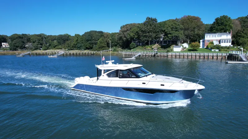 The Image of 2023 Pursuit OS 445 Offshore cruising on a scenic waterway with lush greenery. - 0