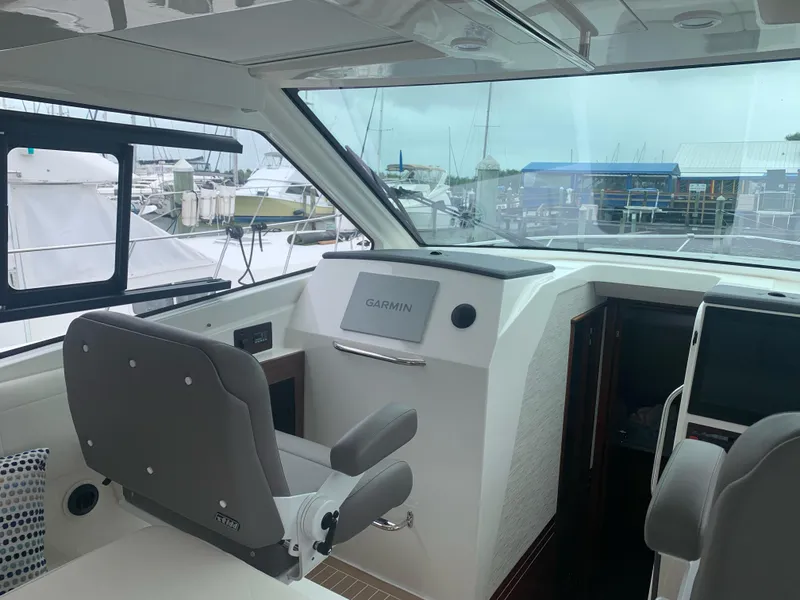 Slide: The Image of 2023 Pursuit OS 445 Offshore helm with Garmin navigation, featuring comfortable seating and marina view. - 10