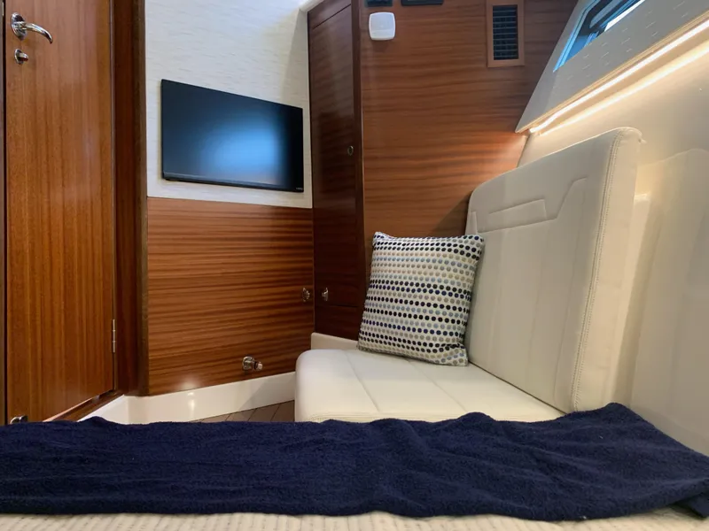 Slide: The Image of 2023 Pursuit OS 445 Offshore cabin interior with sofa, TV, and wooden paneling. - 12