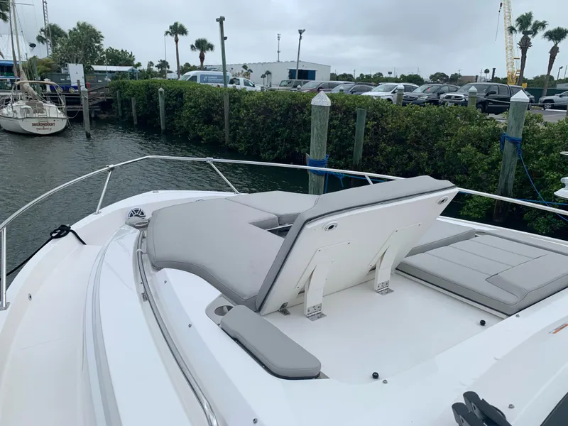 Slide: The Image of 2023 Pursuit OS 445 Offshore boat with cushioned seating, docked near lush greenery. - 14