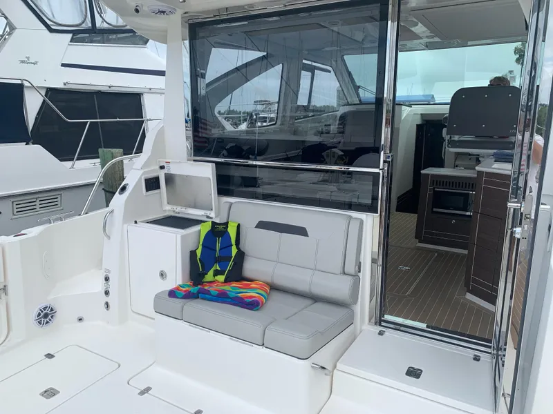 Slide: The Image of 2023 Pursuit OS 445 Offshore boat interior with seating, colorful towel, and life jacket. - 5
