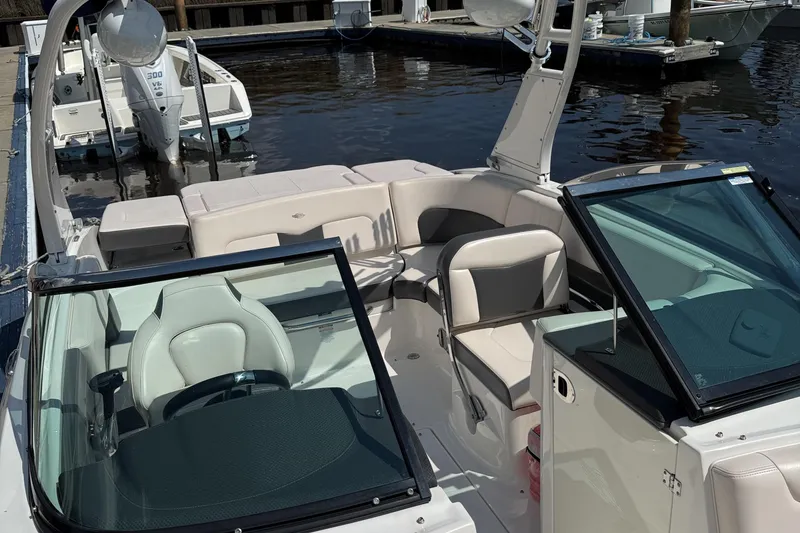 Slide: The Image of 2017 Chaparral 227 SSX boat interior with seating and steering wheel, docked by the water. - 12