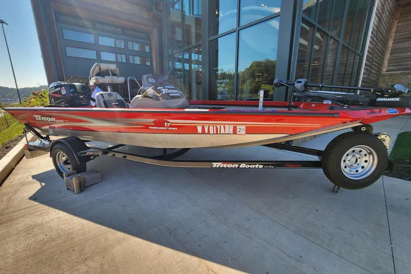Slide: The Image of 2006 Triton TX17 boat on trailer, red and silver design, parked outside a building. - 0