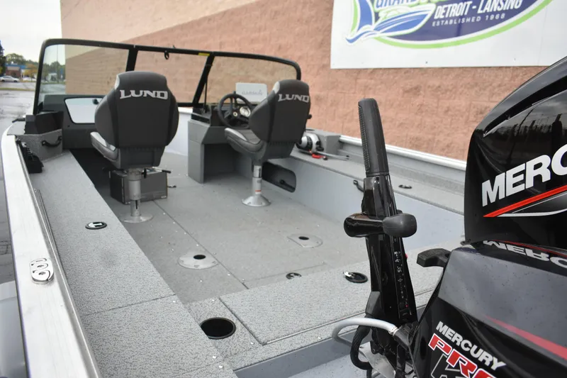 Slide: The Image of 2024 Lund 1875 Alaskan Sport boat interior with Mercury engine, featuring seating and steering console. - 9