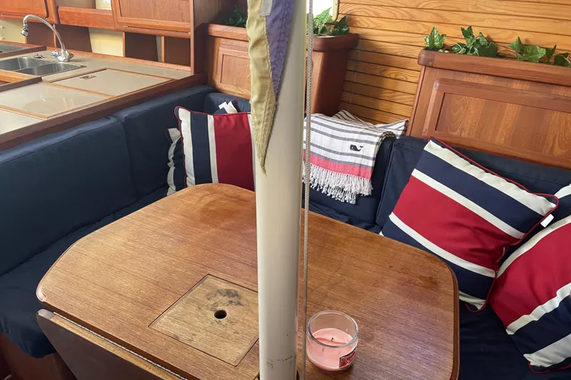 Slide: The Image of Cozy 1994 Hunter Legend 37.5 yacht interior with wooden table, striped cushions, and a candle. - 17