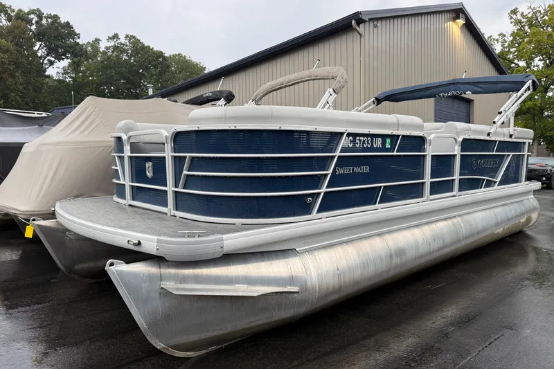Slide: The Image of 2022 Godfrey Sweetwater pontoon boat parked outdoors near a building. - 1