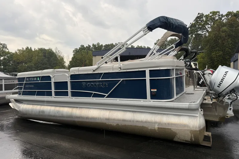 Slide: The Image of 2022 Godfrey Sweetwater pontoon boat with Honda outboard motor, parked outdoors. - 2