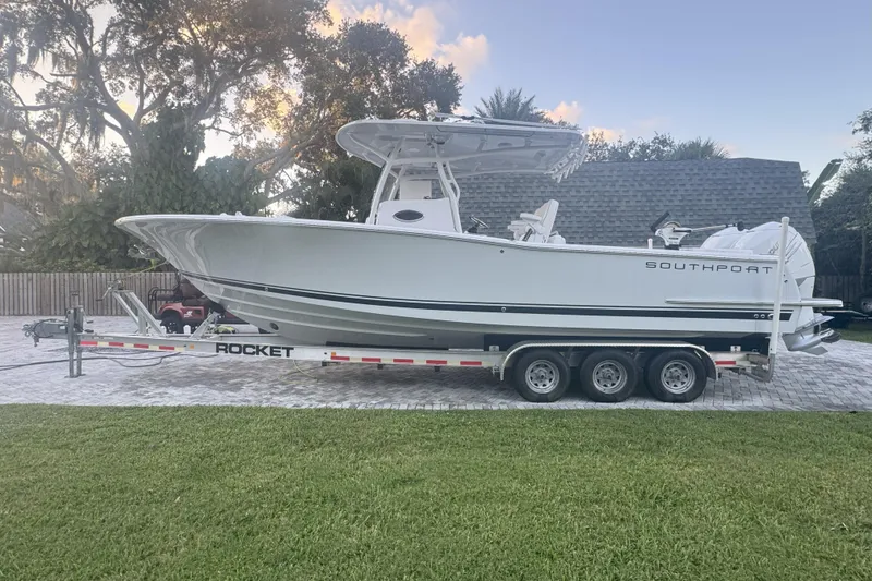 Slide: The Image of 2023 Southport 30 FE boat on a trailer, parked outdoors with trees in the background. - 8