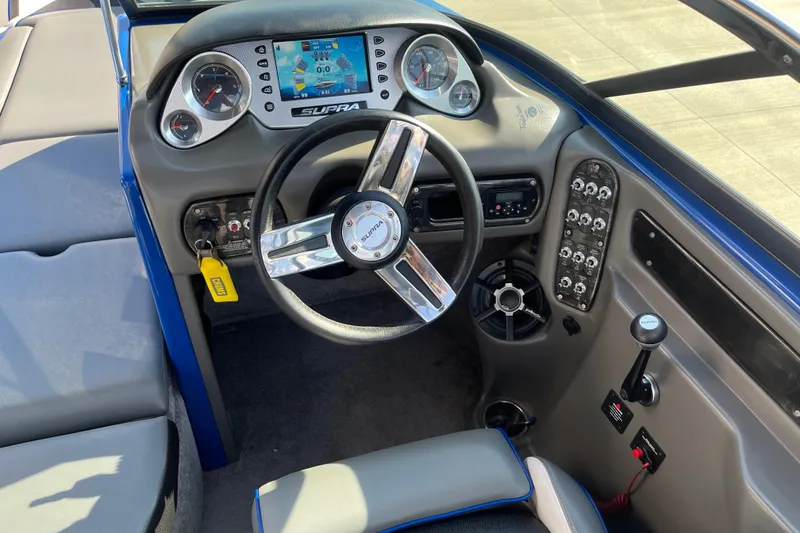 Slide: The Image of 2012 Supra Launch 242 boat dashboard with steering wheel and control panel. - 10