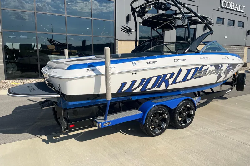 Slide: The Image of 2012 Supra Launch 242 boat with custom graphics on a trailer, parked outside a showroom. - 3