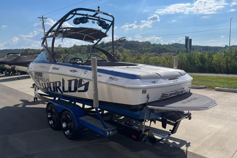 Slide: The Image of 2012 Supra Launch 242 boat on trailer, parked outdoors under a sunny sky. - 6