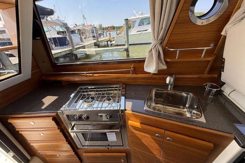 Slide: The Image of Interior of 2026 Ranger Tugs R-29 CB with kitchen, stove, and sink, overlooking marina. - 13