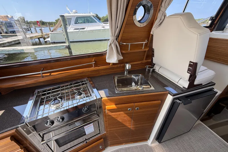 Slide: The Image of Interior of 2026 Ranger Tugs R-29 CB with kitchen amenities and scenic window view. - 14