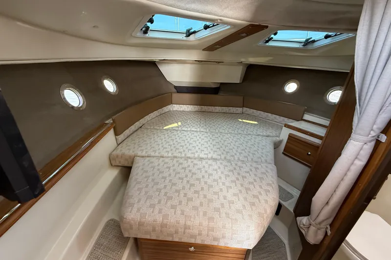 Slide: The Image of 2026 Ranger Tugs R-29 CB cabin interior with cozy bed and porthole windows. - 18