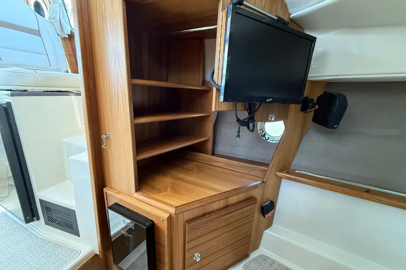 Slide: The Image of 2026 Ranger Tugs R-29 CB interior with wooden shelves and mounted TV. - 19