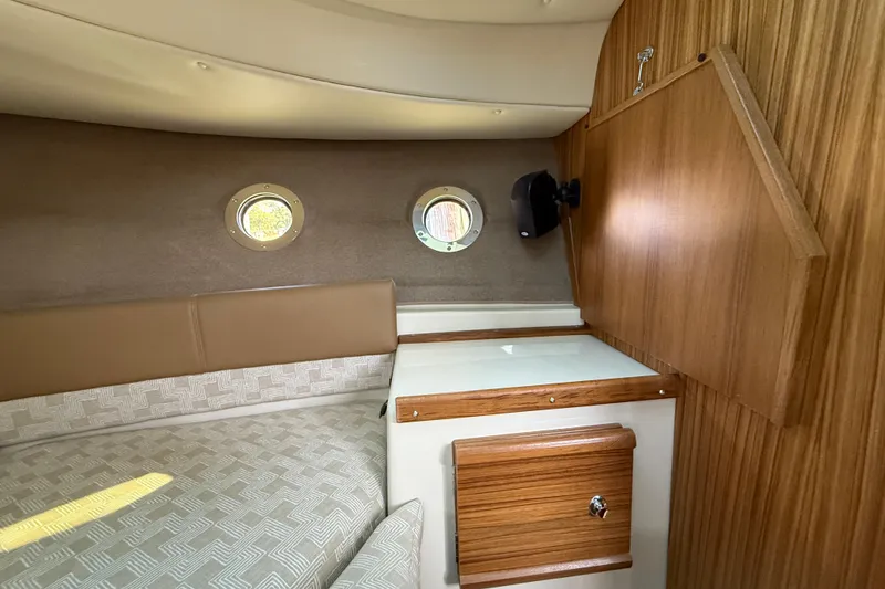 Slide: The Image of 2026 Ranger Tugs R-29 CB cabin interior with wood finish and porthole windows. - 20