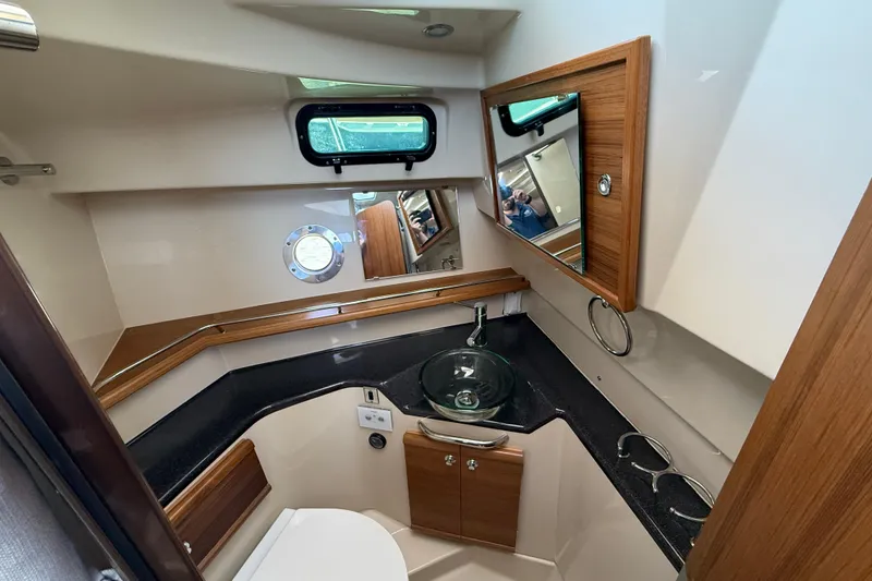 Slide: The Image of 2026 Ranger Tugs R-29 CB bathroom with modern sink, wood accents, and porthole window. - 21