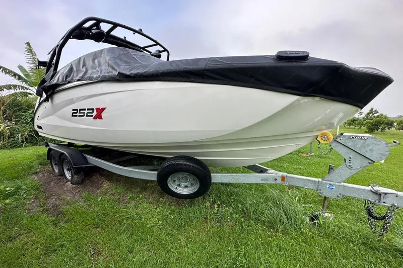 The Image of 2022 Yamaha Boats 252XE on trailer by the ocean, under a clear sky. - 0