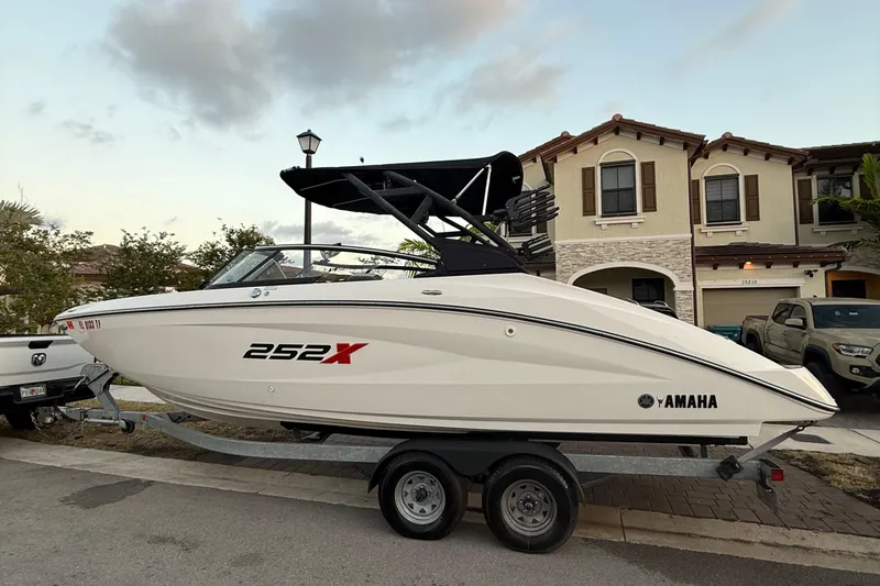 Slide: The Image of 2022 Yamaha Boats 252XE on trailer by the sea, clear blue sky. - 1