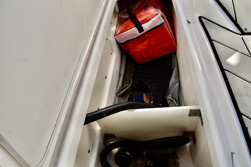 Slide: The Image of Storage compartment in 2022 Yamaha Boats 252XE, containing a red bag and equipment. - 31