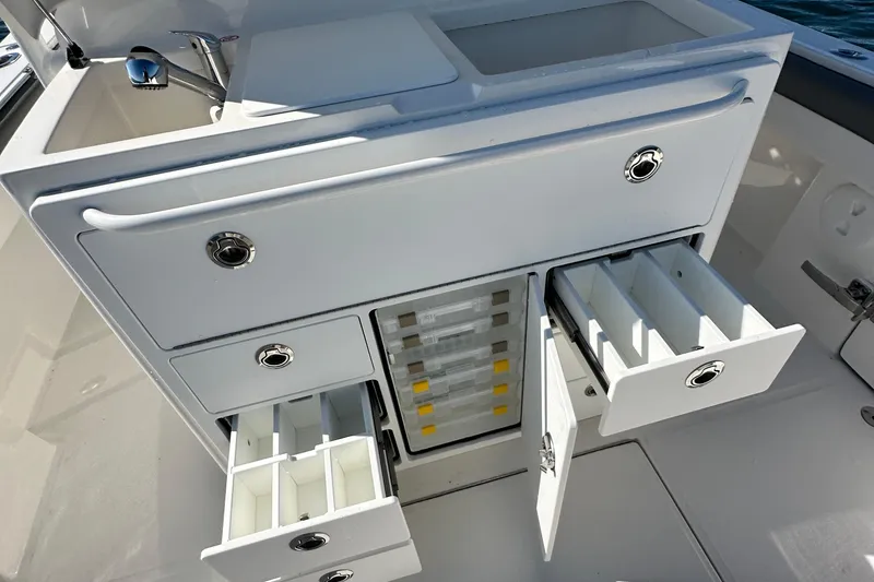 Slide: The Image of 2024 Regulator 34 boat storage compartments with drawers and sink, showcasing organized fishing gear space. - 32