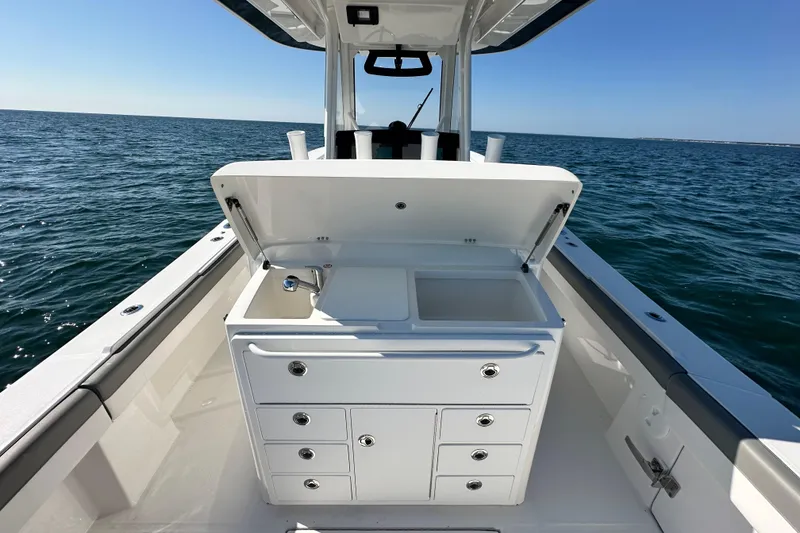 Slide: The Image of 2024 Regulator 34 boat with open storage compartment and sink, cruising on calm ocean waters. - 33