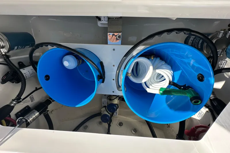 Slide: The Image of 2024 Regulator 34 boat storage compartment with blue buckets and coiled hose. - 41