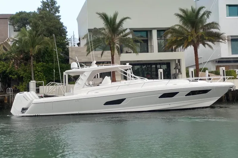 The Image of 2022 Intrepid 477 Evolution yacht docked near modern waterfront home. - 0