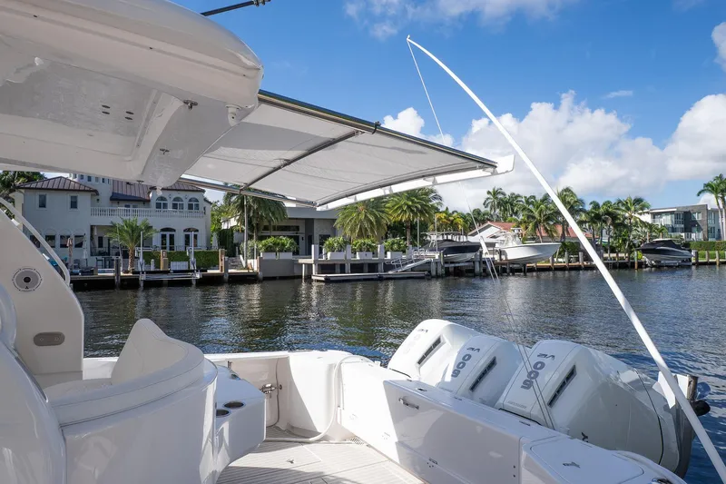 Slide: The Image of 2022 Intrepid 477 Evolution boat with canopy, docked by waterfront homes. - 2