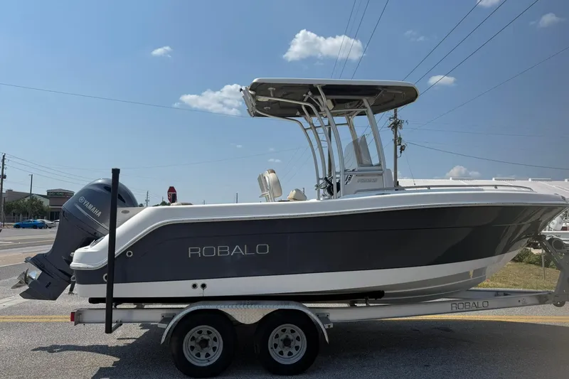 The Image of 2017 Robalo R222ES boat on trailer with Yamaha engine, parked roadside under clear sky. - 0