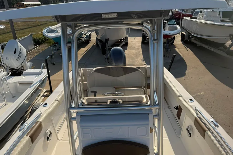 Slide: The Image of 2017 Robalo R222ES boat with T-top and seating, docked among other boats. - 23