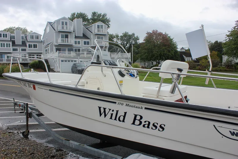 Slide: The Image of 2007 Boston Whaler 170 Montauk boat named "Wild Bass" on a trailer near houses. - 11