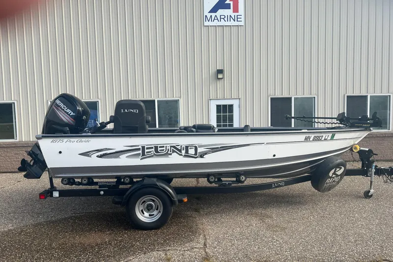 Slide: The Image of 2016 Lund 1875 Pro Guide boat on trailer outside marine dealership. - 0