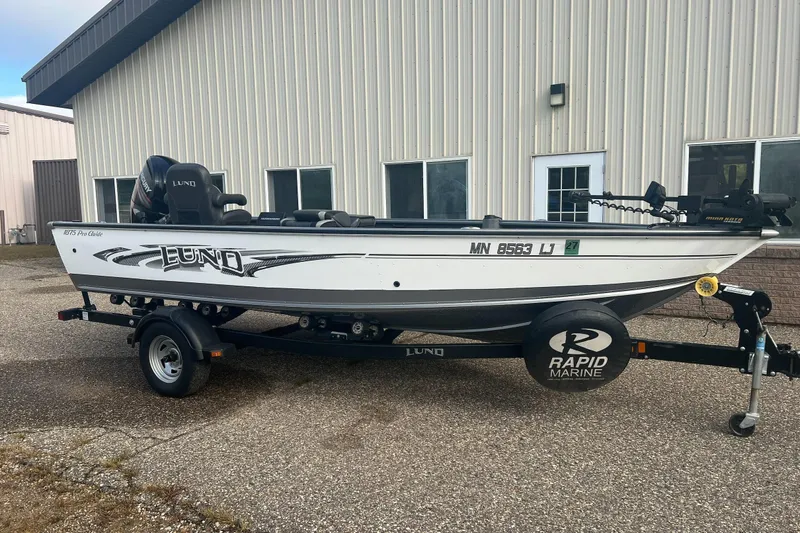 Slide: The Image of 2016 Lund 1875 Pro Guide boat on trailer, parked outside a building. - 1